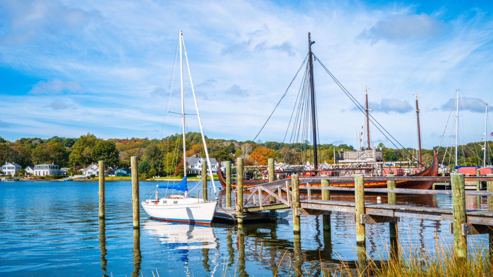 Commercial dock with moored white boat and sailing ship in Mystic, Connecticut