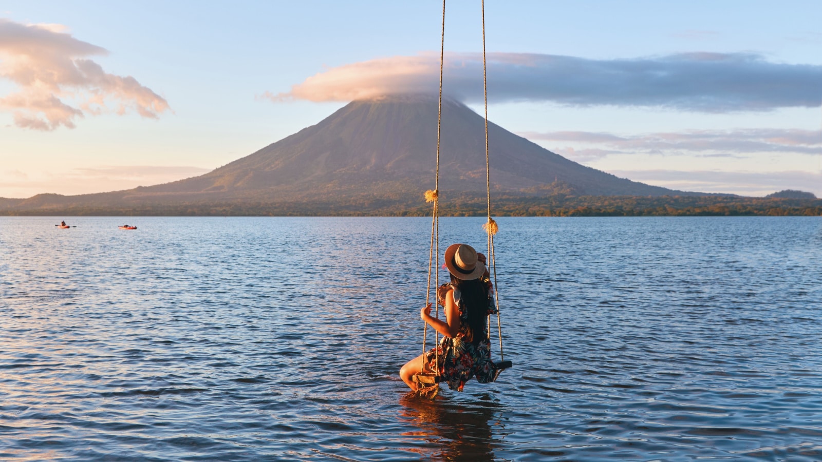 A Back view of woman sitting on a swing overlooking the volcano concenpcion on ometepe island, Nicaragua.