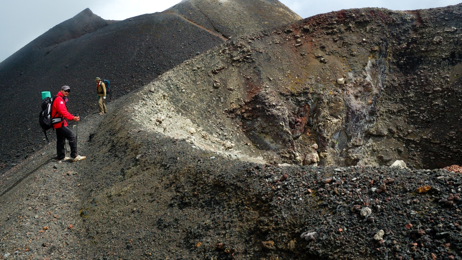 MOUNT CAMEROON, CAMEROON - CIRCA JUNE, 2008 - Two hikers from Europe resting near Mt.Cameroon volcano crater. Landscape is volcano ash covered by eruption that took place in 2000.