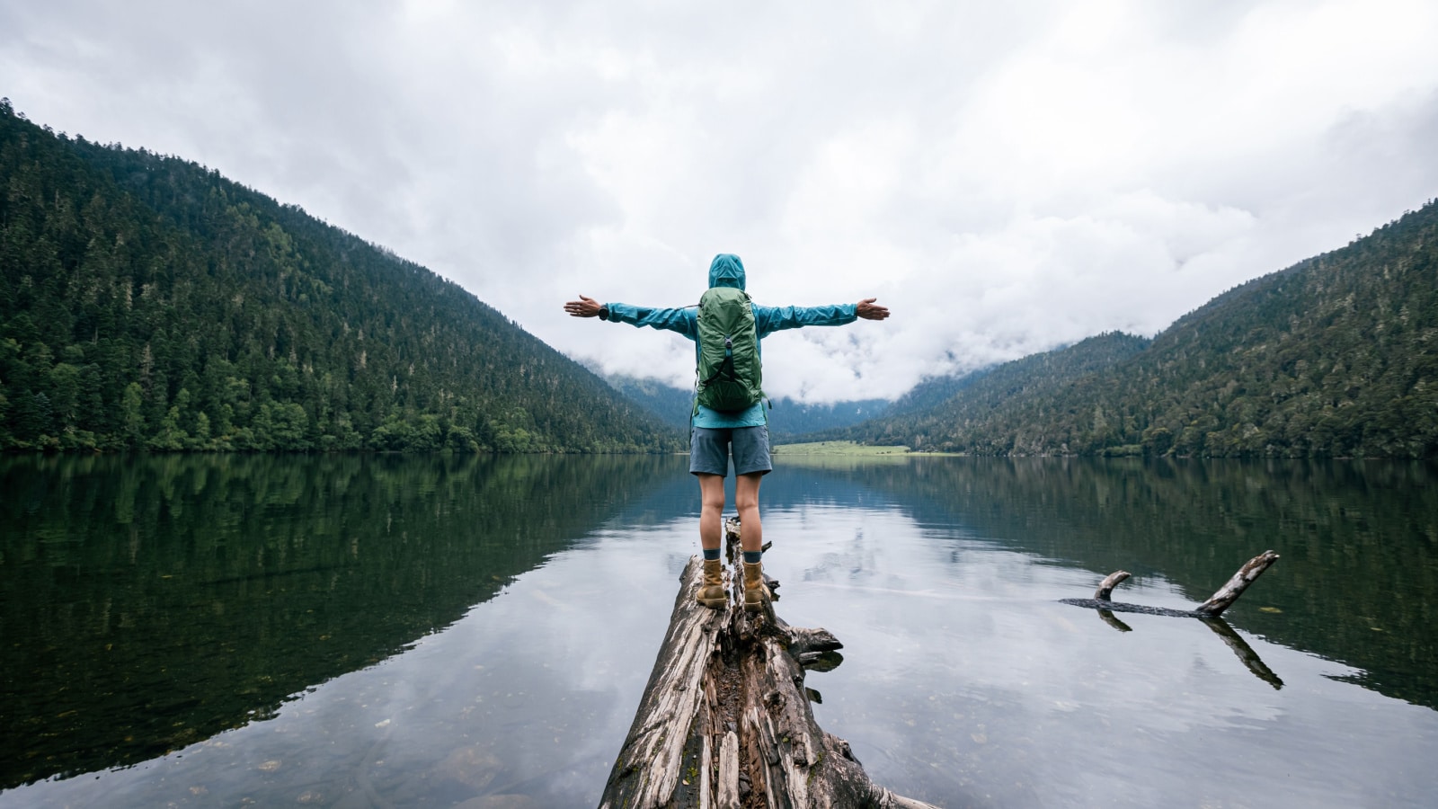 Woman traveller open arms to foggy high altitude mountains