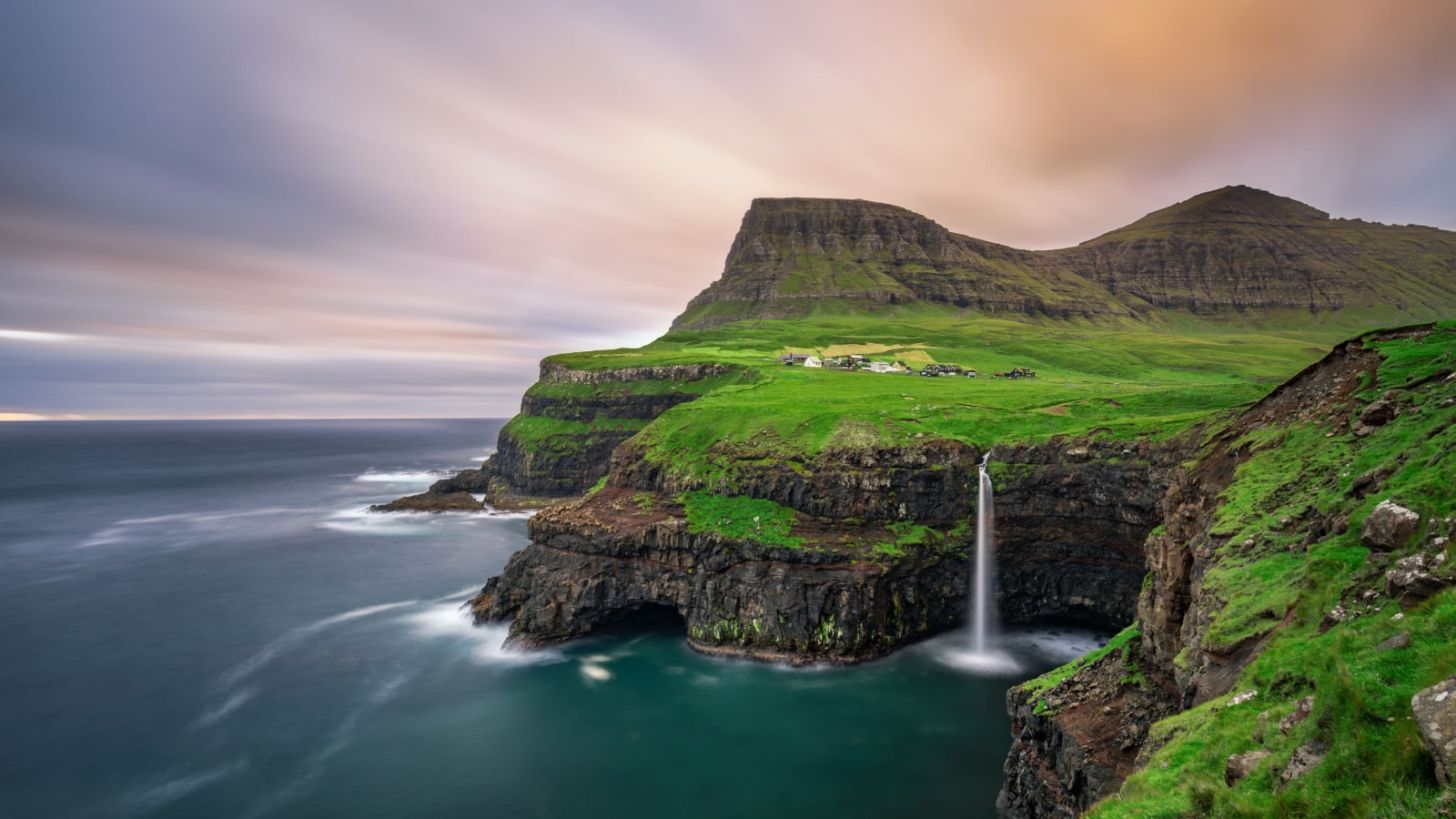 Gasadalur village and its iconic waterfall, Vagar, Faroe Islands, Denmark. Long exposure.