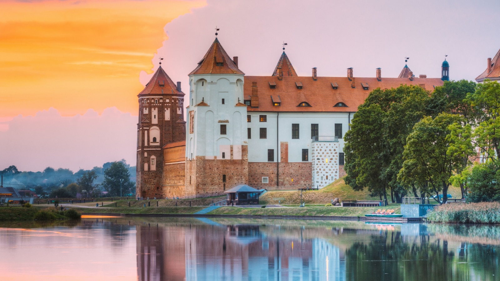 Mir, Belarus. Scenic View Of Castle Complex Mir On Sunny Sunset Sky Background. Old Towers Are Reflected In Lake River Wate