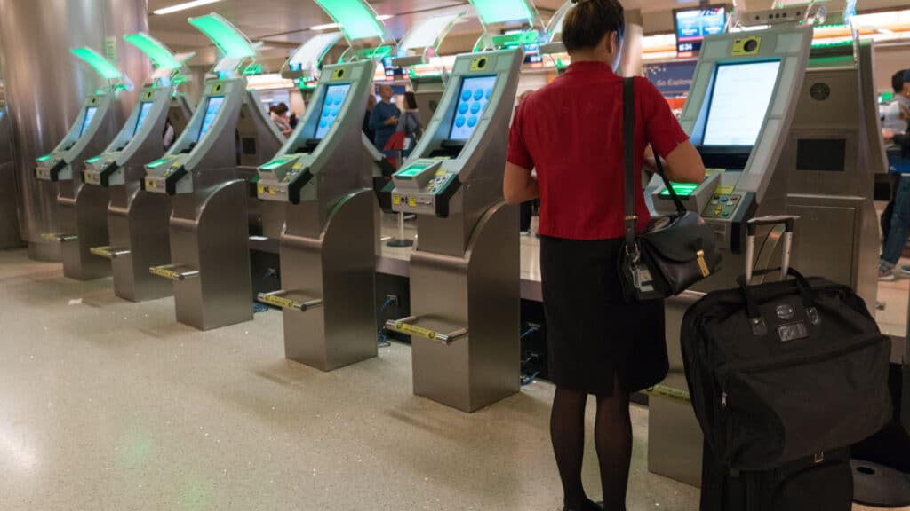 Los Angeles, USA 12, 2017: Young business woman passenger in red dress using custom kiosk for self check and declaration in at LAX Los Angeles International Airport.
