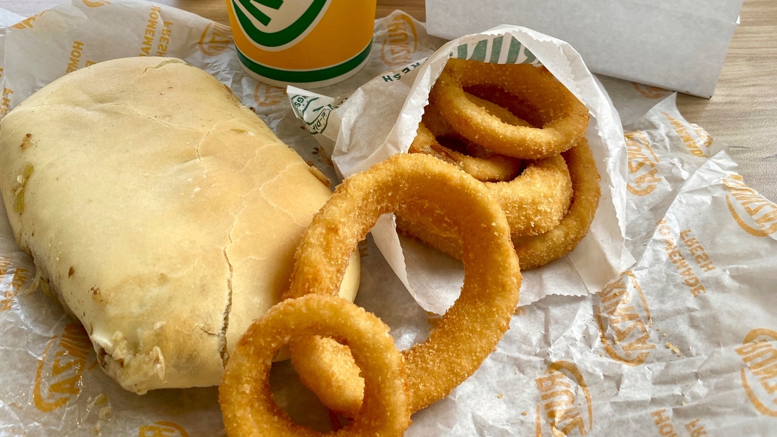 Omaha, Nebraska - 2021: Runza Restaurant meal with a Runza sandwich, onion rings, and drink. Bag with Runza logo and "Runza makes it all better" motto.