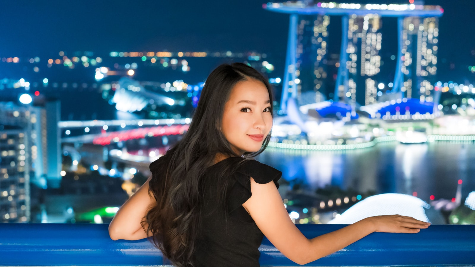 Beautiful Asian women smile and happy with singapore city view at night