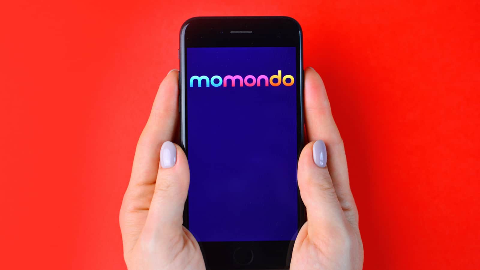 KHARKIV, UKRAINE - JULY 10, 2019: Illustrative editorial of Momondo logo on smartphone screen in female hands.