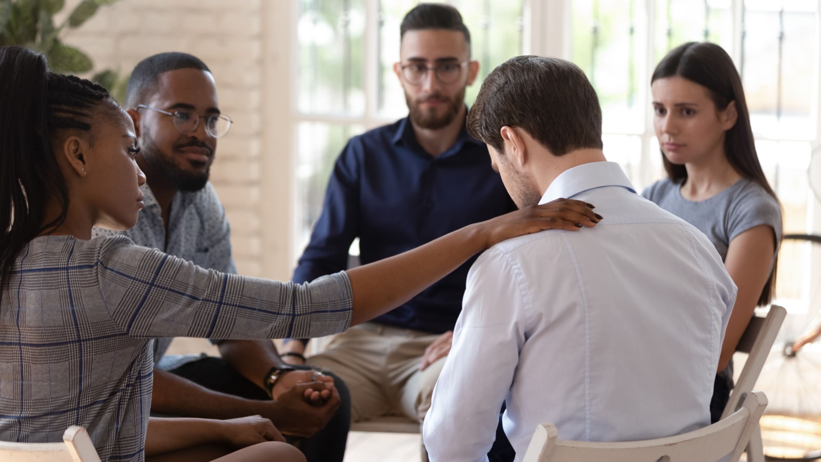 Rear view at upset man feel pain depression problem addiction get psychological support of counselor therapist coach diverse people friend group help patient during therapy counseling session concept