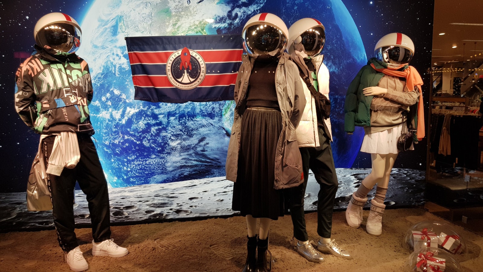 Berlin / Germany - 12 11 2018: Space themed Christmas fashion showcase on background of planet Earth photo with flag. Mannequins in astronaut helmets are displayed in shop window of Berlin city.