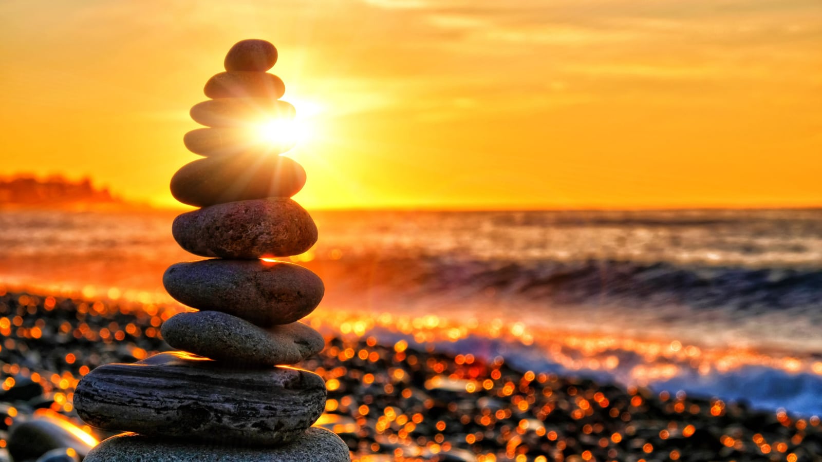 beautiful sunrise over sea beach landscape with stone figure against rising sun background. Closeup view of ocean shore at sunset with rocks. Time to collect stones scene