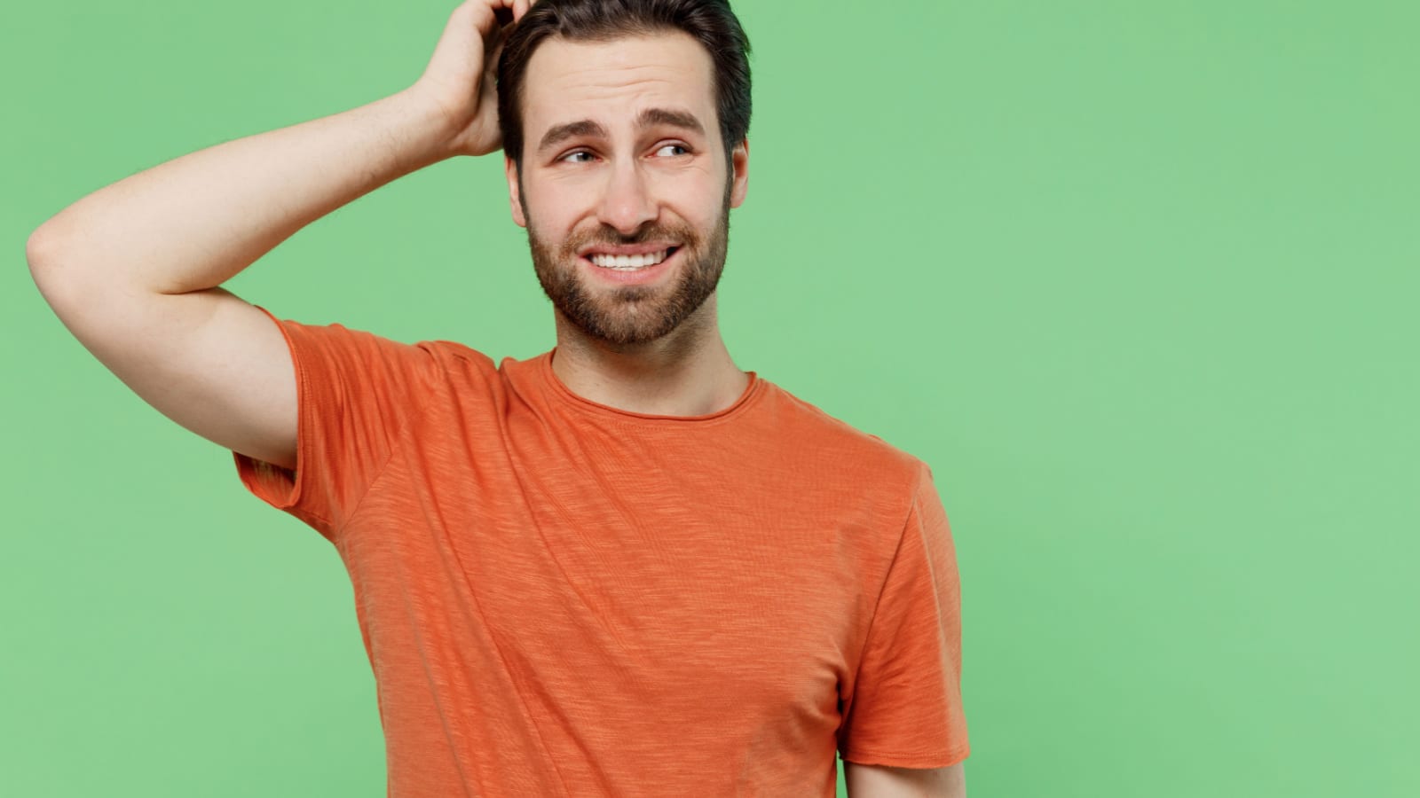 Young mistaken worried sad caucasian man 20s wear casual orange t-shirt look aside scratch hold head isolated on plain pastel light green color background studio portrait. People lifestyle concept.