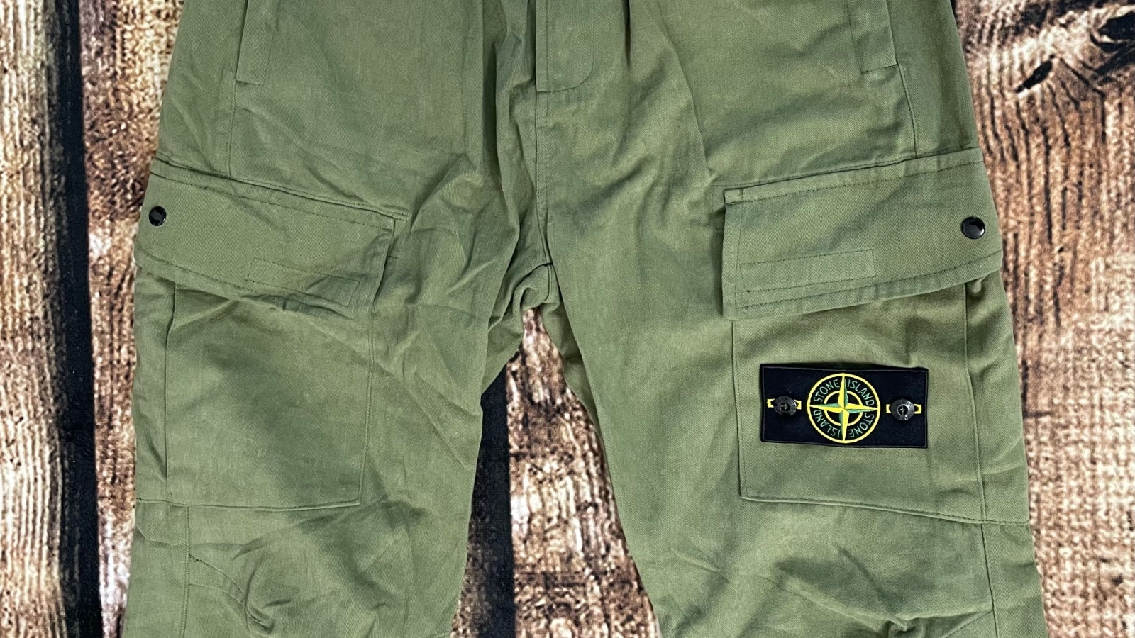 Seoul, South Korea - January 11th 2023 : Stone Island army green color cargo pant close up picture on wood patterned carpet