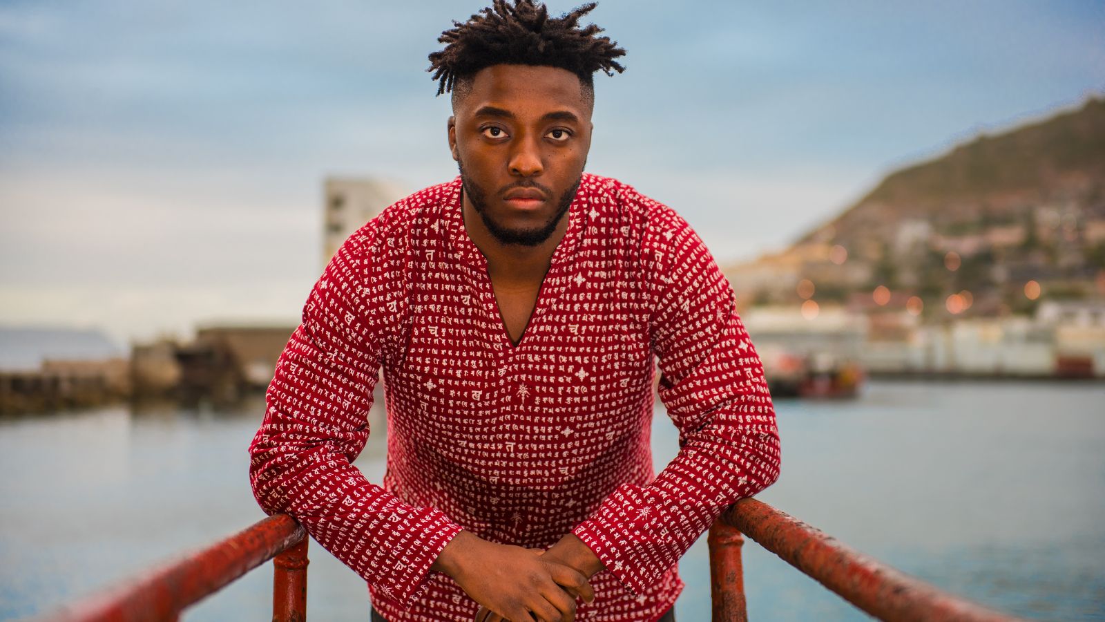 CAPE TOWN, SOUTH AFRICA - CIRCA 2021: Portrait of young African man in a red shirt at sunset