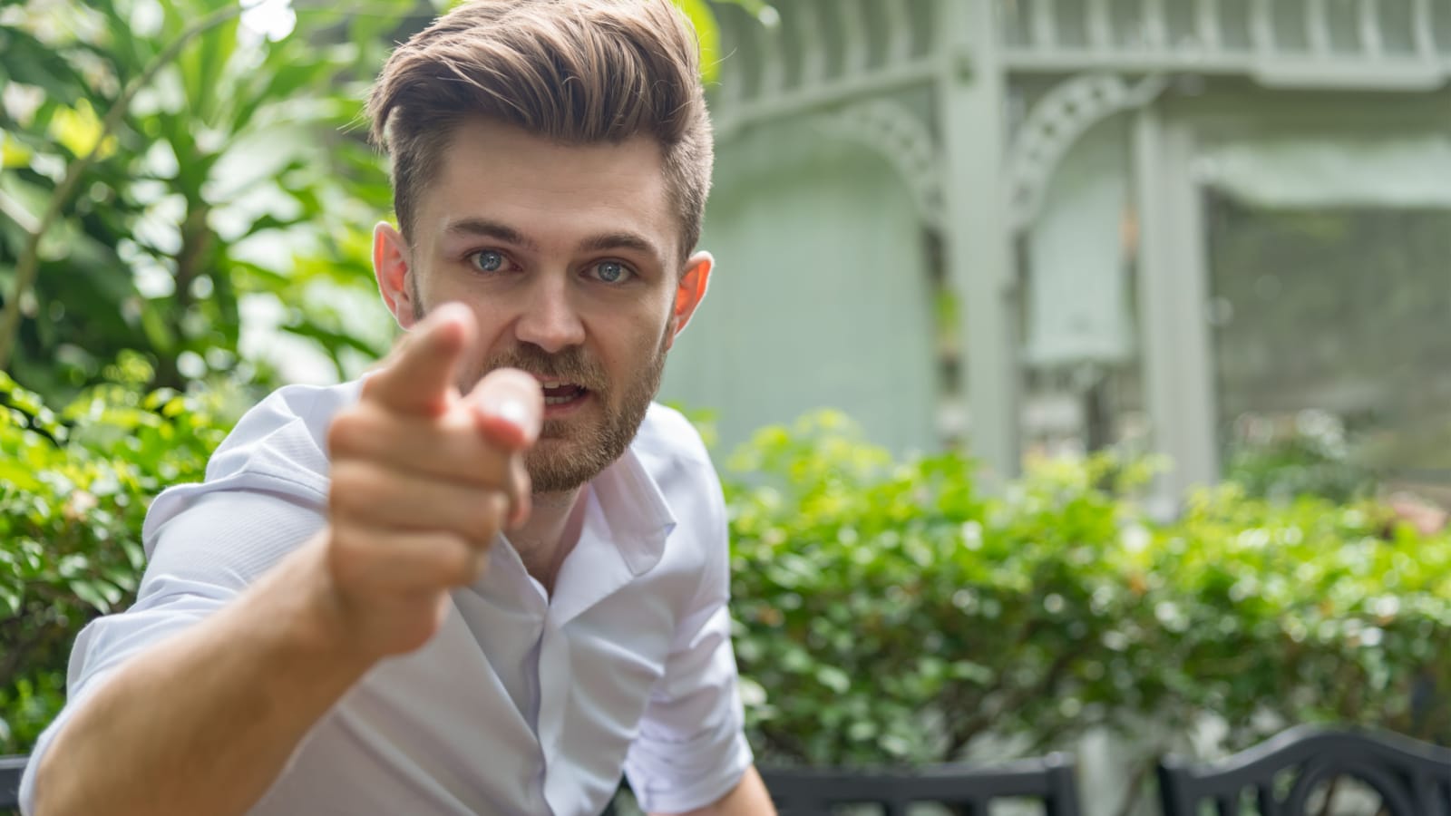 Young furious caucasian businessman shouting and pointing camera . Angry man and cursing .Anger, emotions, aggression, Negative human emotions concept