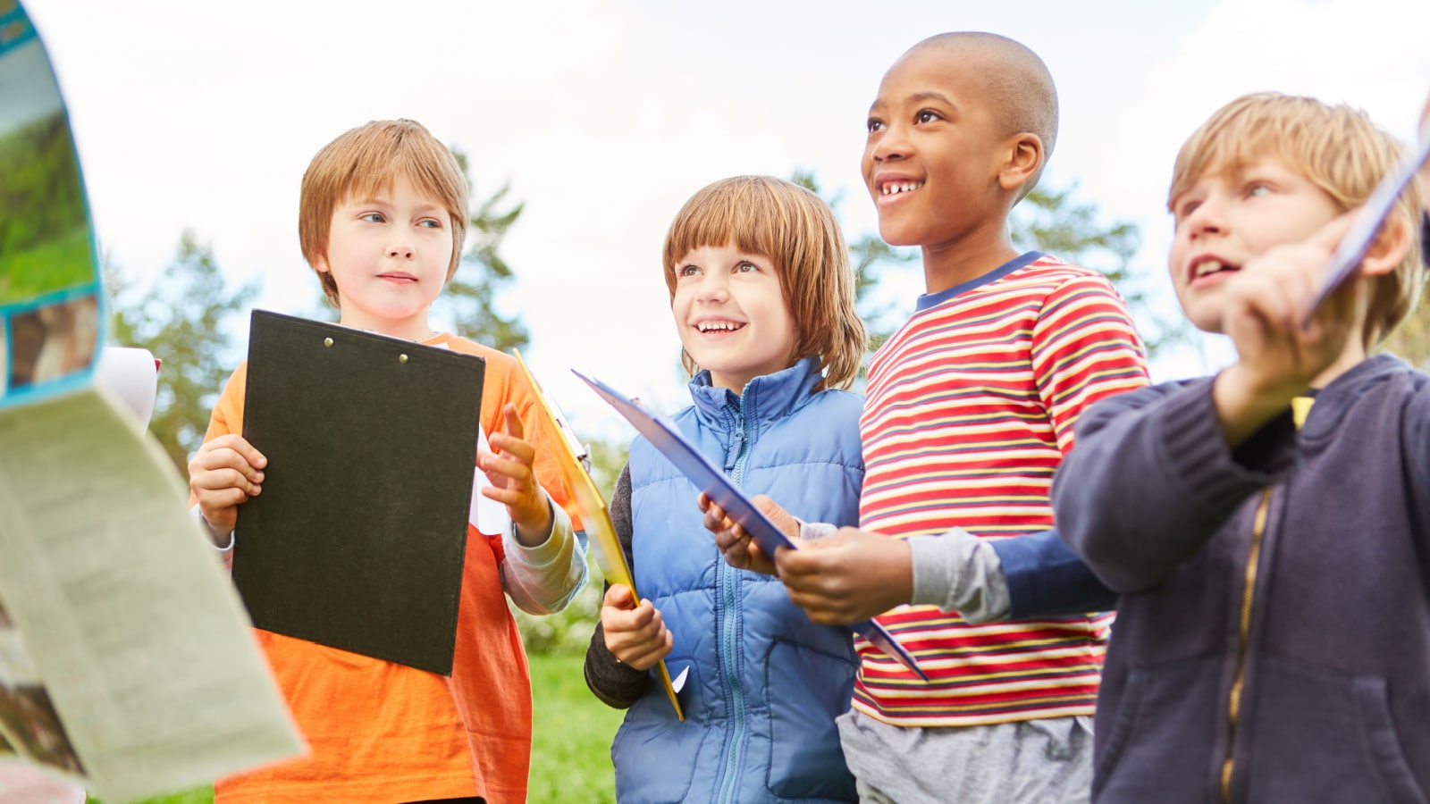 Group of kids with clipboards on scavenger hunt in nature at children's birthday party