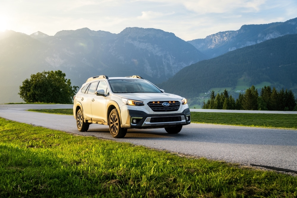Schladming, Austria - August 25, 2024: White family SUV Subaru Outback in the evening at sunset on the road in the mountains. Off-road car in the Alps in nature between the mountains.