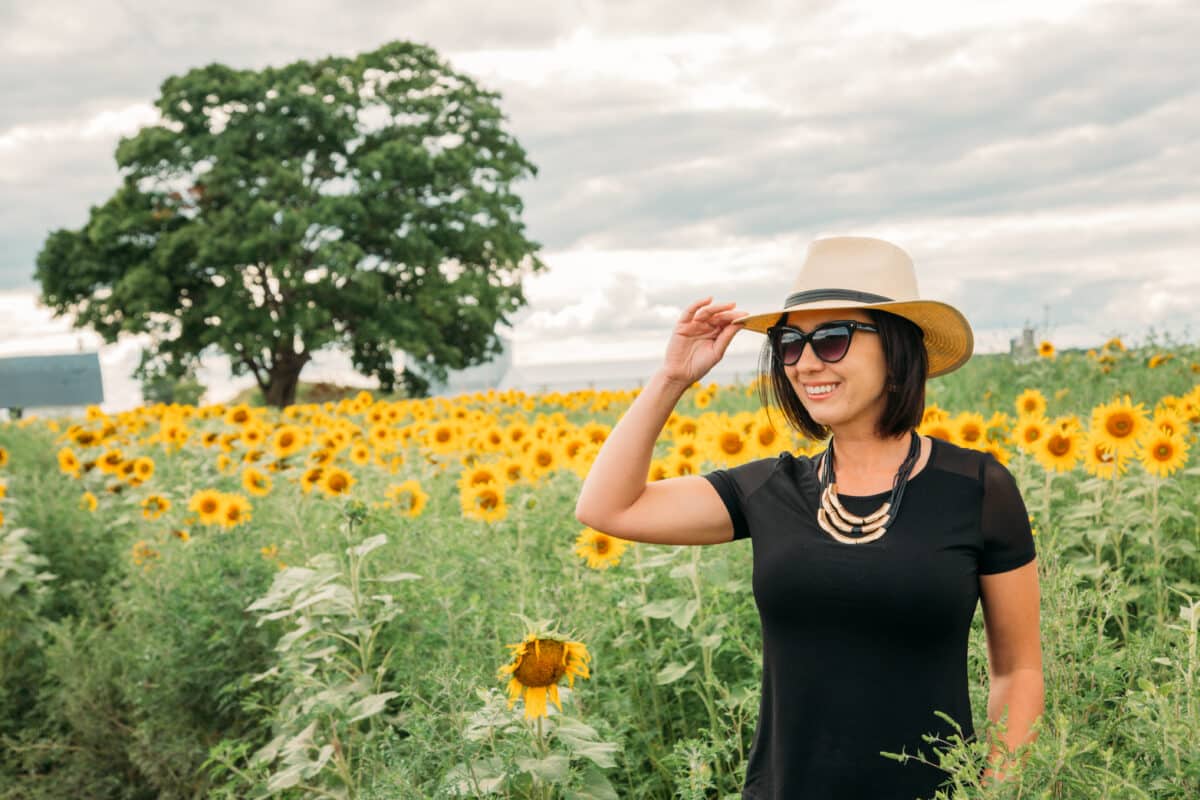 Wearing a straw fedora and black Anatomie t shirt in a field of sunflowers