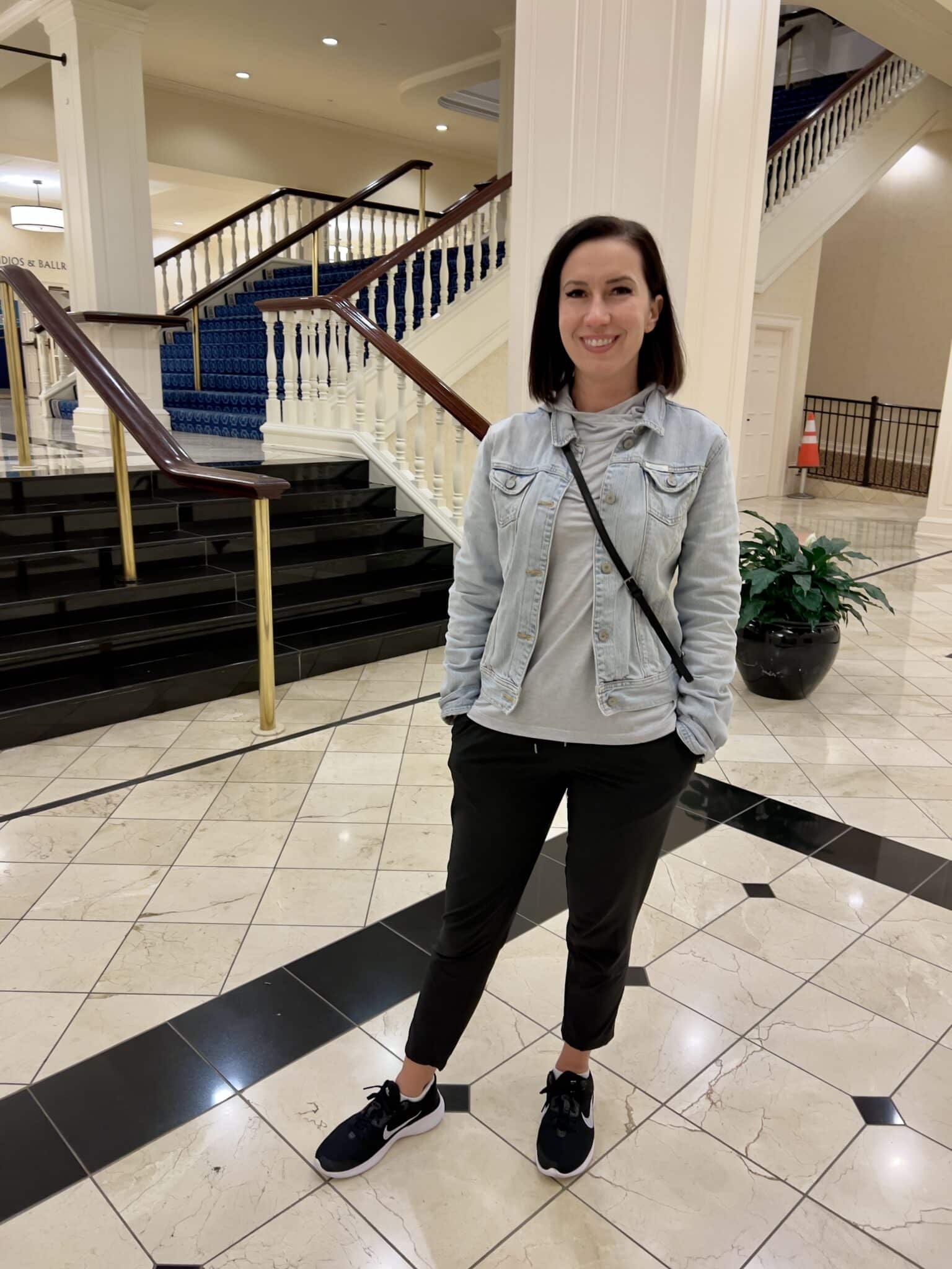 Wearing a jean jacket over a Free fly hoodie with black pants and black nike sneakers standing in a hotel lobby