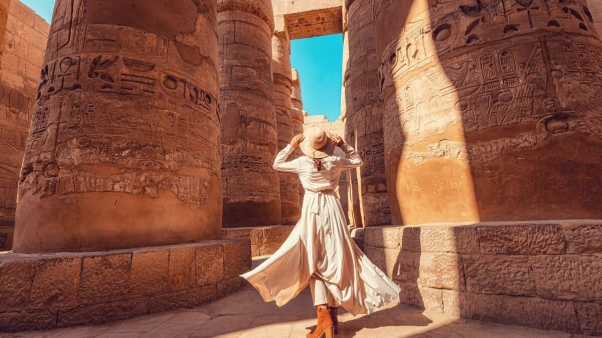 Woman traveler explores the ruins of the ancient Karnak temple in the city of Luxor in Egypt. Great row of columns with carved hieroglyph