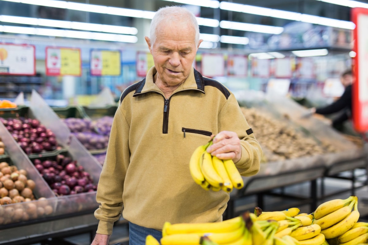 senor man pensioner buying banana in grocery