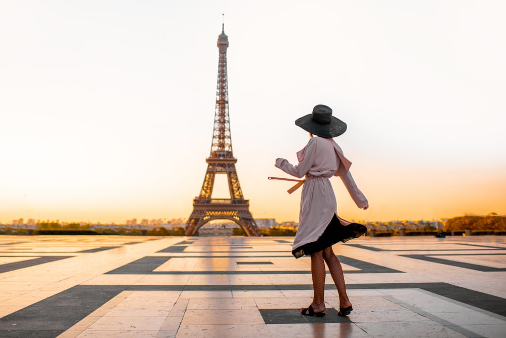 Woman dressed in coat and hat walking on the famous square with great view on the Eiffel tower early in the morning in Paris