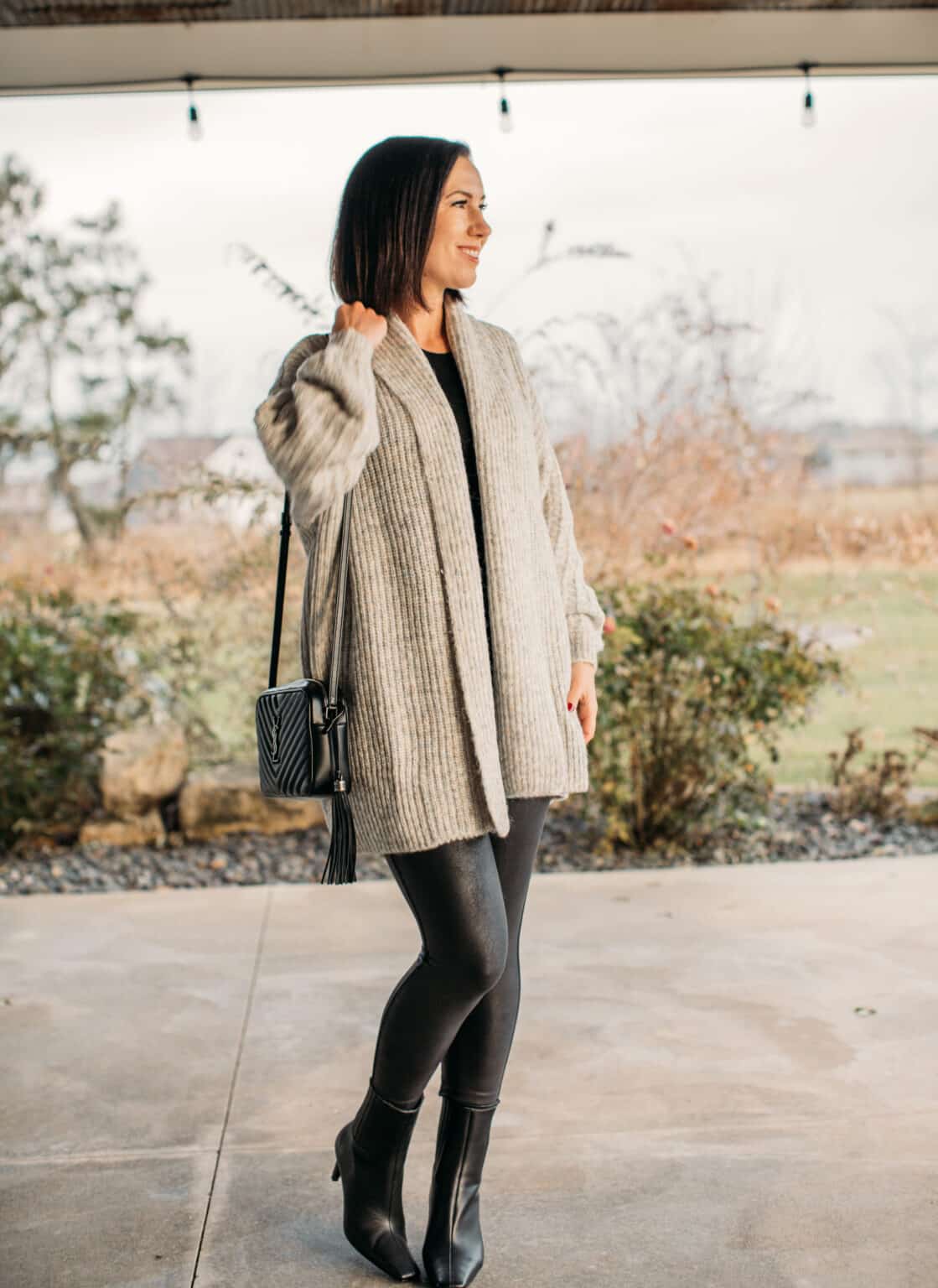 Lindsey wearing a long grey cardigan with faux leather leggings and black ankle boots