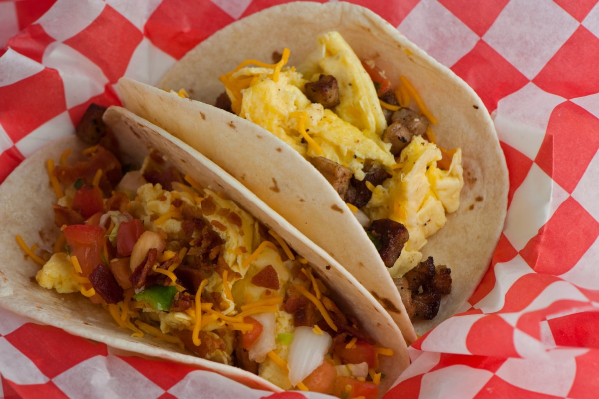 Breakfast tacos. Crispy flour and corn tortillas filled with eggs, sausage, bacon, beef, cheese, sour cream, salsa and guacamole. Classic Tex-Mex or Mexican restaurant breakfast favorite.