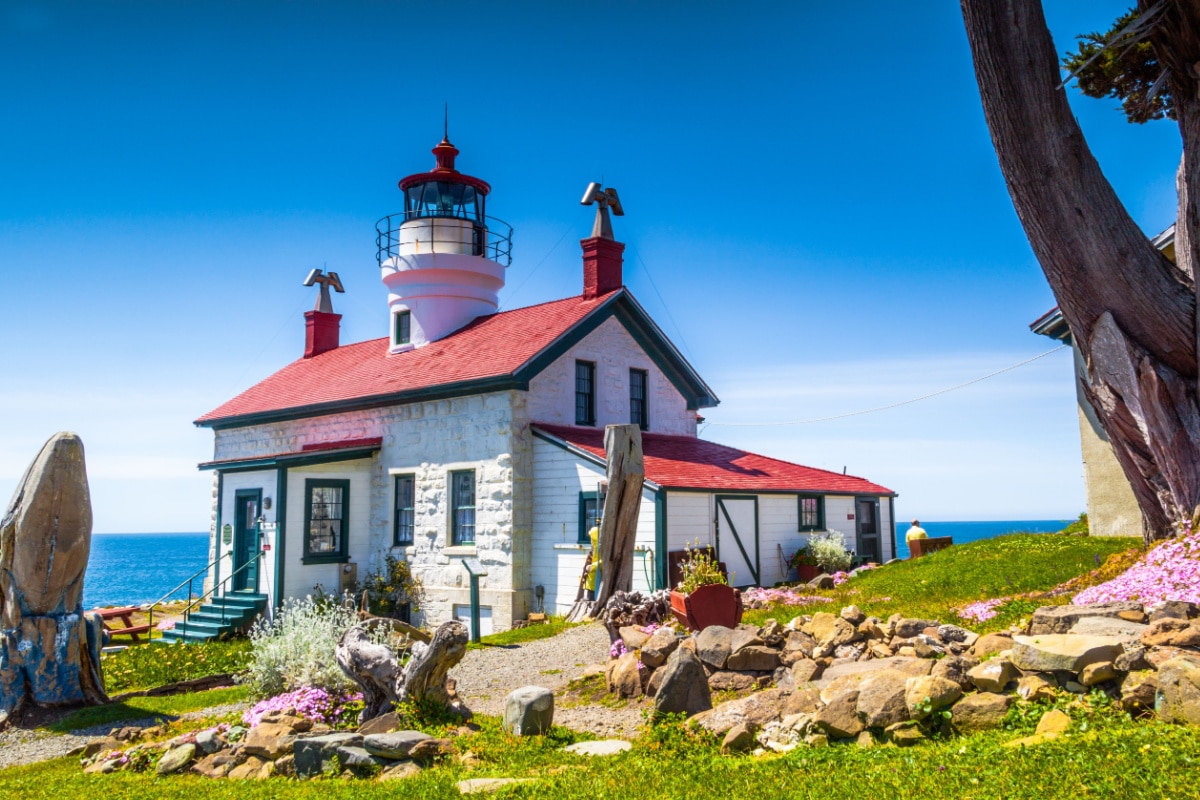 Colorful view of the Battery Point Lighthouse in Crescent City California, green grass, colorful flowers, blue sky on a sunny day