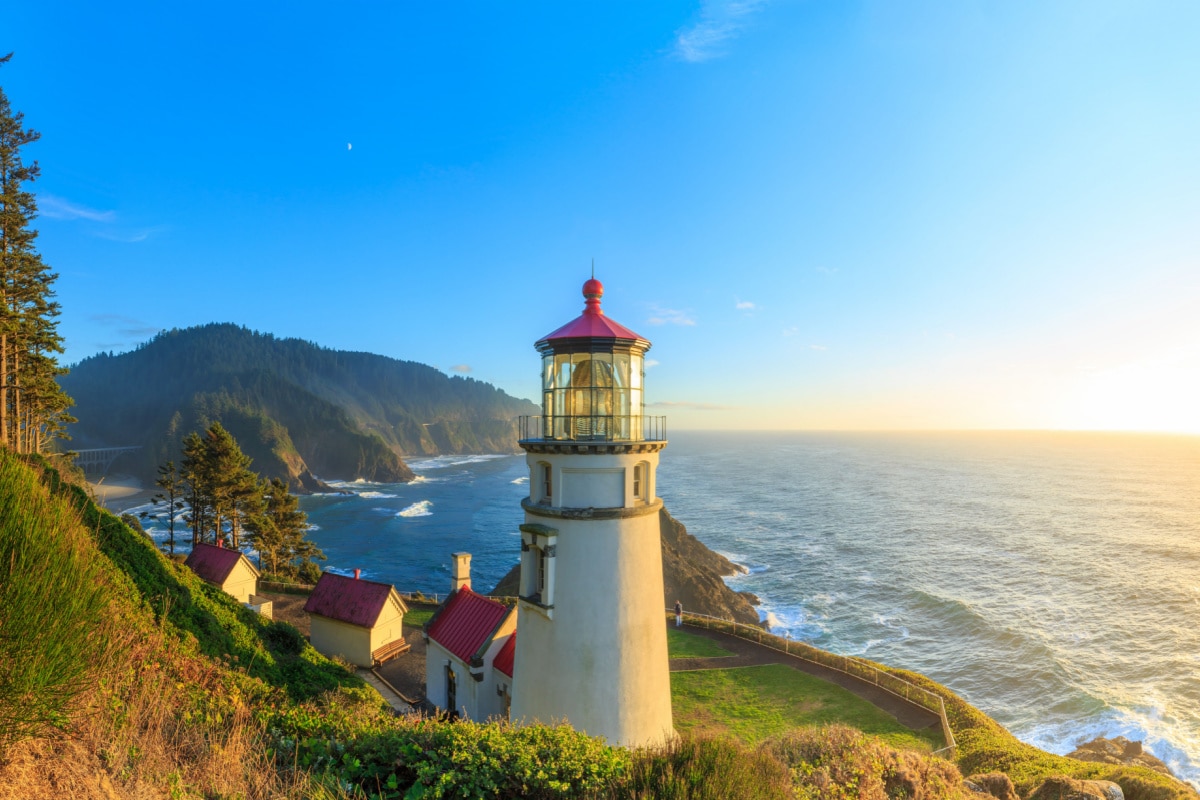 The sun sets in the sea and illuminates Heceta Head Lighthouse, Oregon, USA.