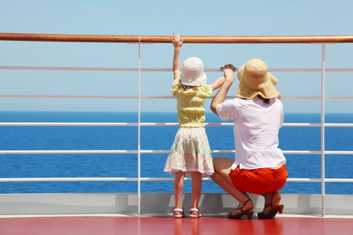 behind mother and her daughter standing on deck of yacht and they look far aboard