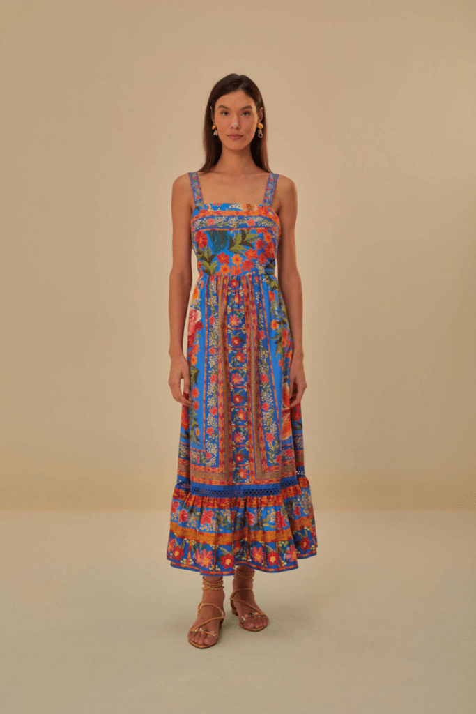 A women modeling a colorful Farm Rio brand of maxi dress with a tropical garden-themed design