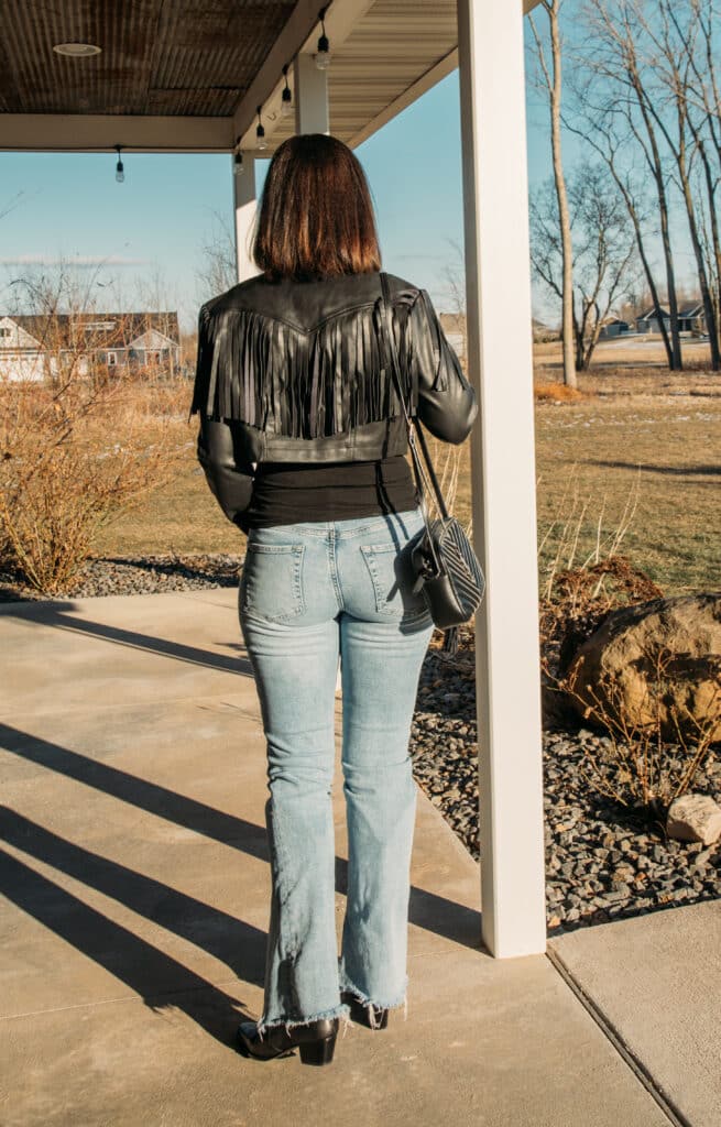 Lindsey shows the back of her black leather jacket with fringe, and flared jeans