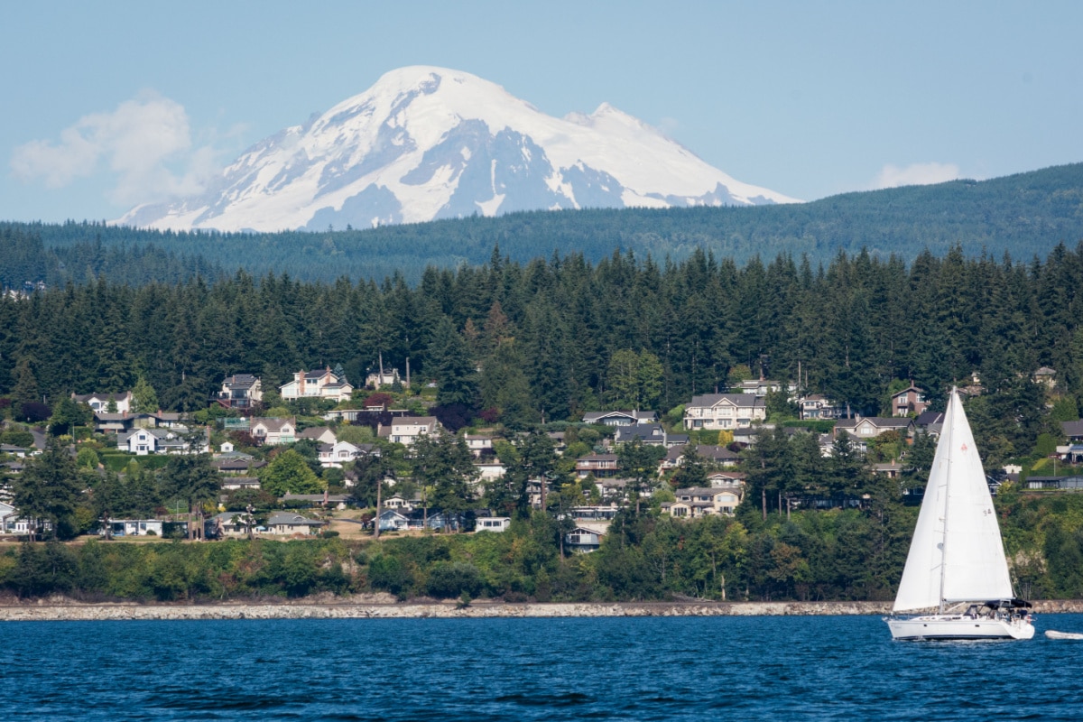 A photo of Mount Baker with a sailboat and houses in the Bellingham town area.