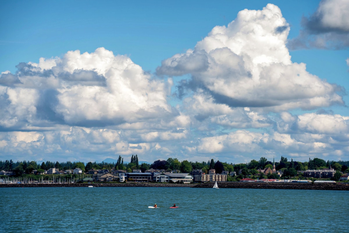 Kayakers on Water in Foreground on Bellingham Bay with Dramatic Clouds Over Industrial Area