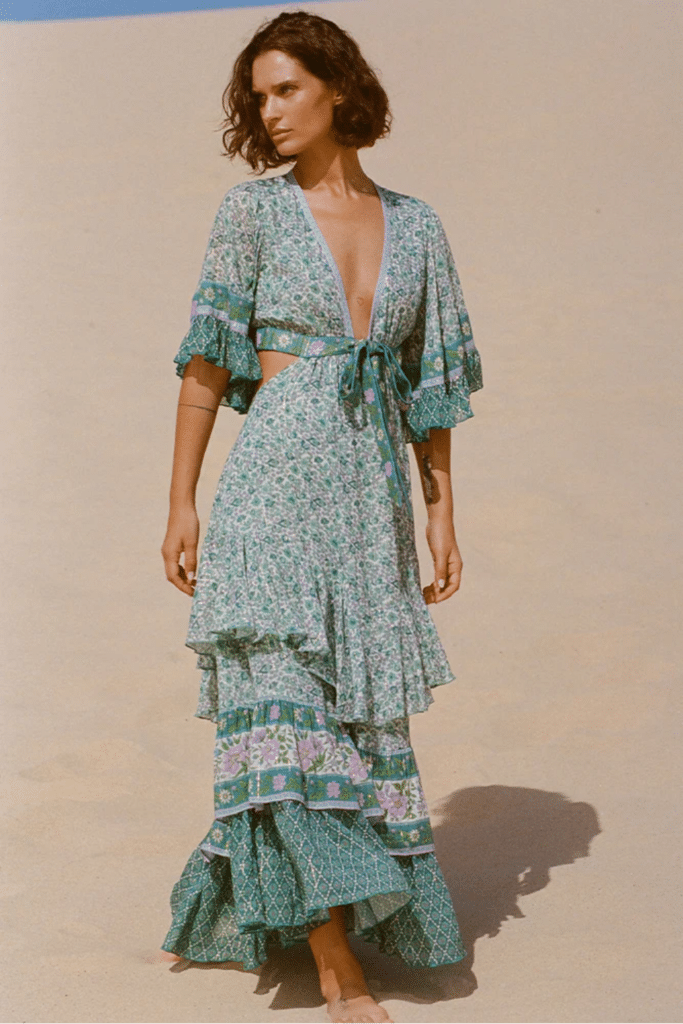 Model wearing a maxi dress in jade color featuring a high-low hem and adjustable front tie with keyhole sides