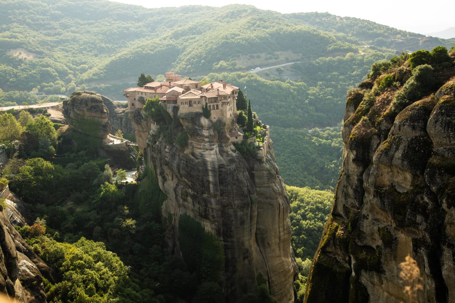 A monastery is perched a top a rock formation in Meteora Greece in the morning hours