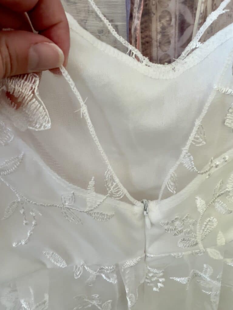 A closeup of the back of the wedding dress shows loose threads and questionable stitching 