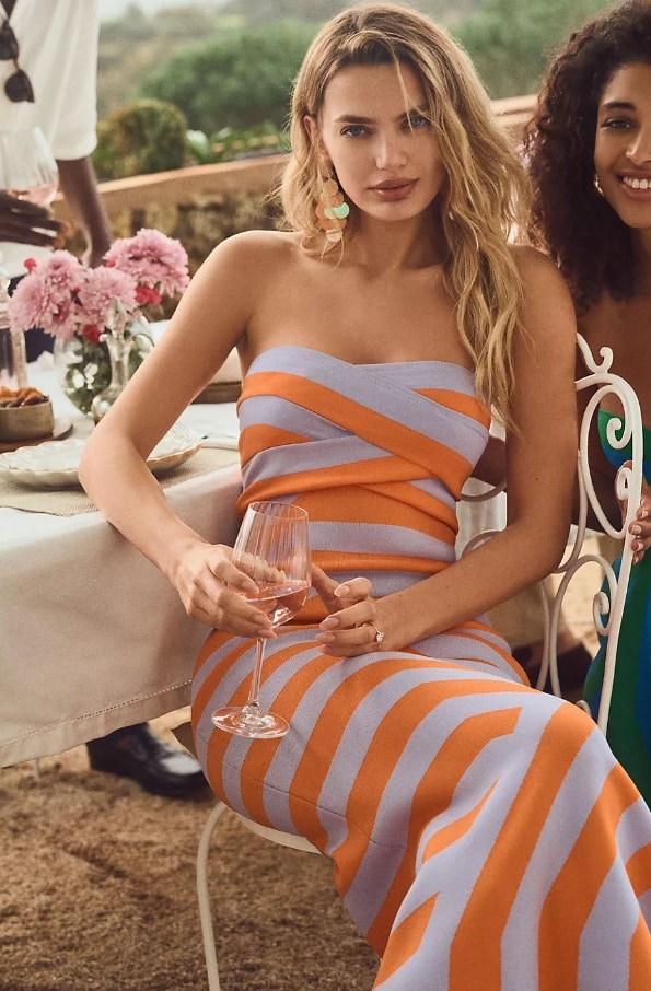 A young blonde woman wears the The Wolf Gang Sleeveless Midi Dress at a wedding