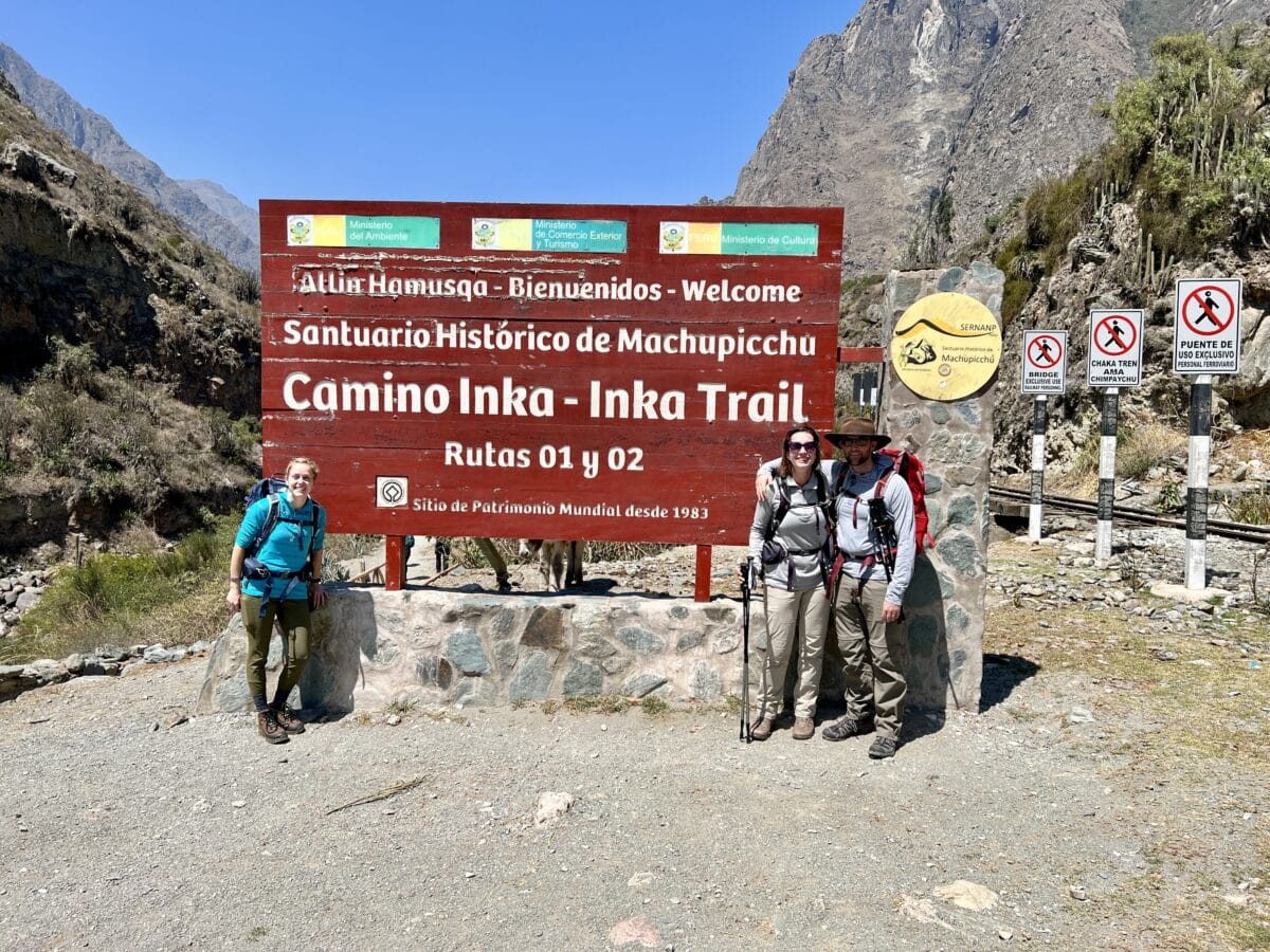 The Camino del Inca Trek sign in peru with three hikers posing by it