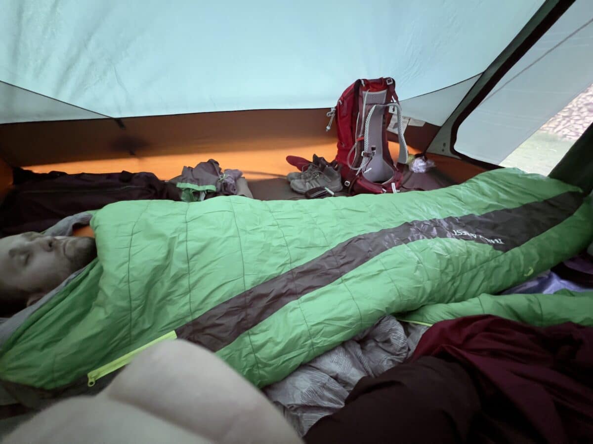 Zac in a green sleeping bag in the tent.