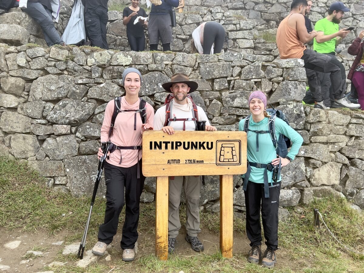 3 hikers posing with a sign on the Inca Trail