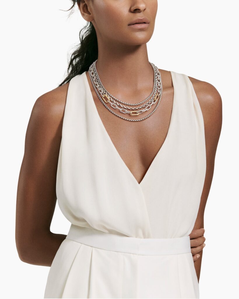 Woman in white dress modeling chain necklace in gold and silver