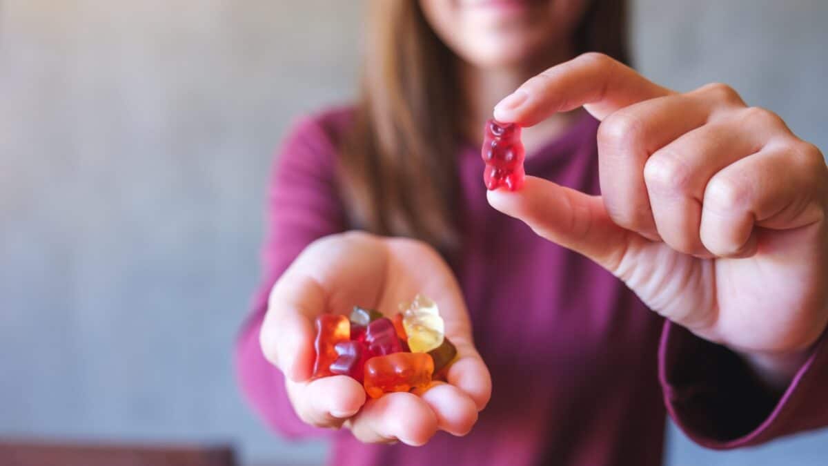 Closeup image of a young woman holding and showing at a red jelly gummy bears