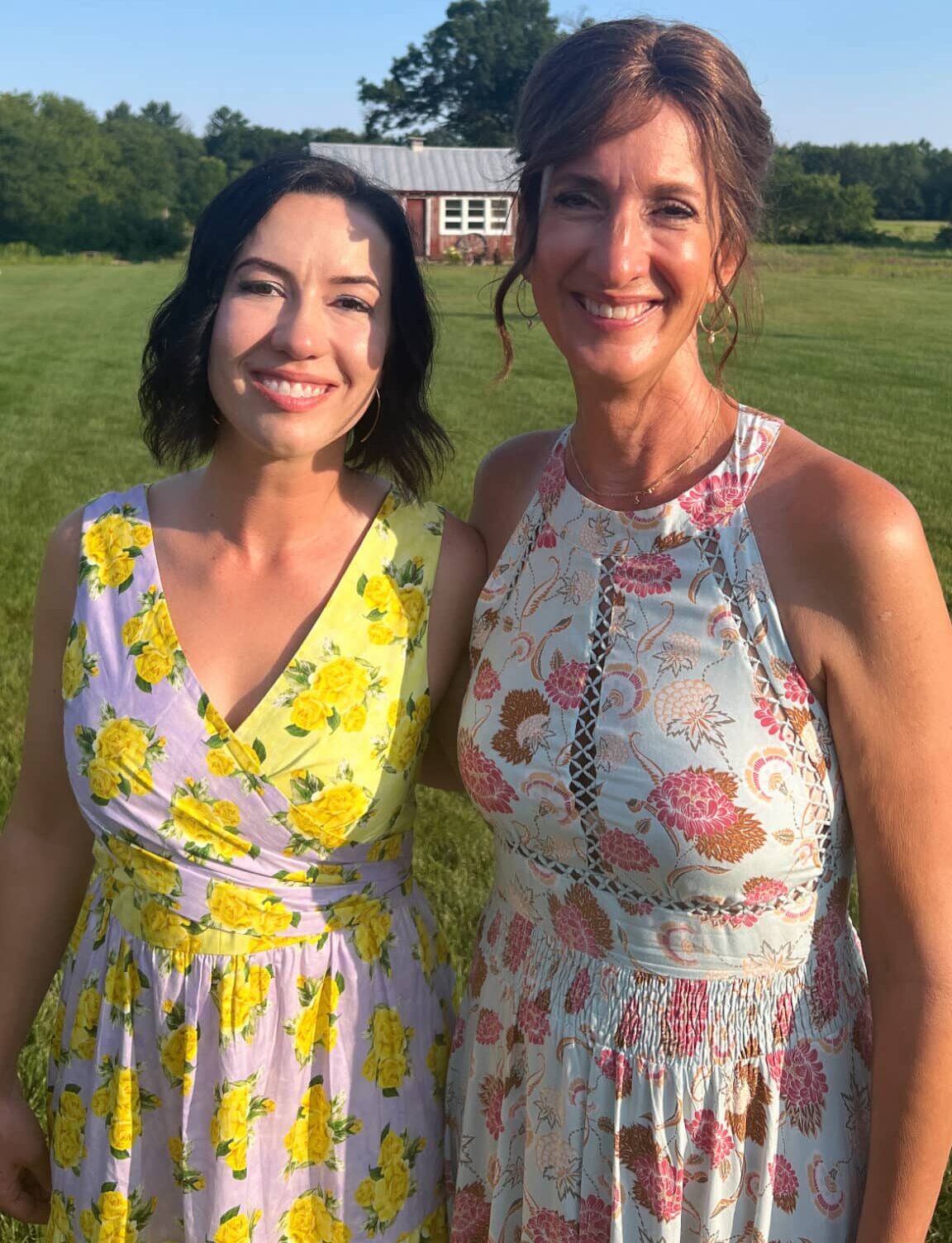 Lindsey and her mom smiling at the camera both wearing floral dresses