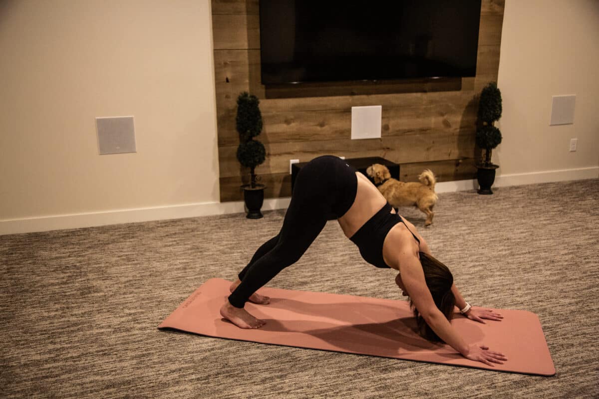 Lindsey doing downward dog in her IUGA outfit with her dog in the background