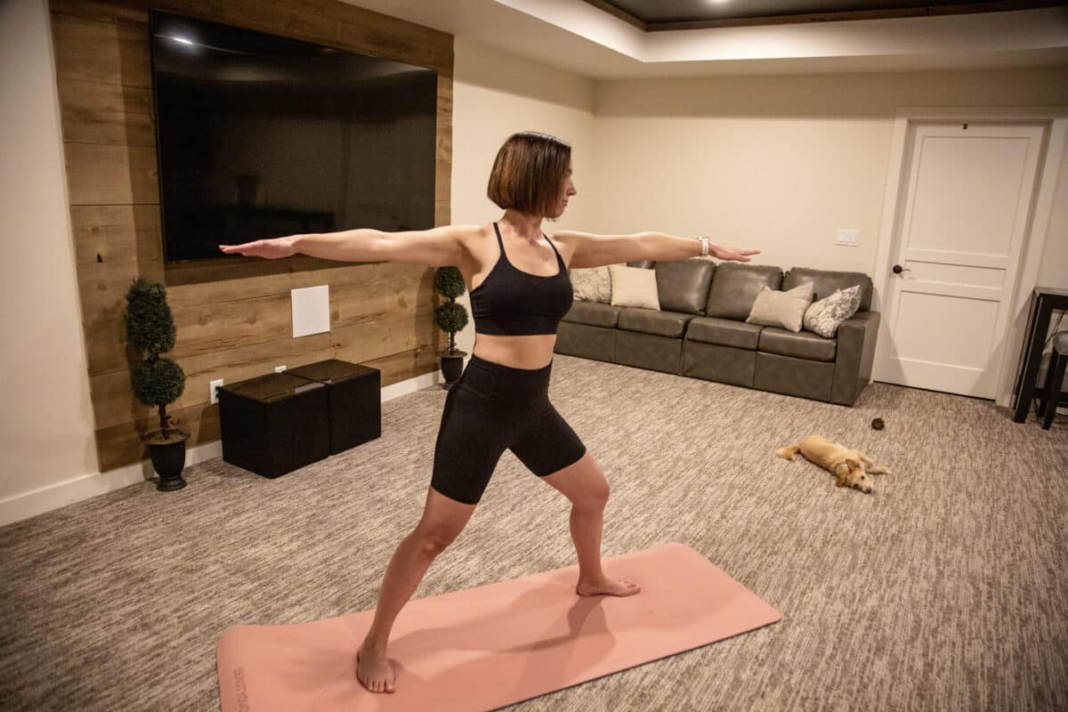 Lindsey doing a yoga pose while her dog naps