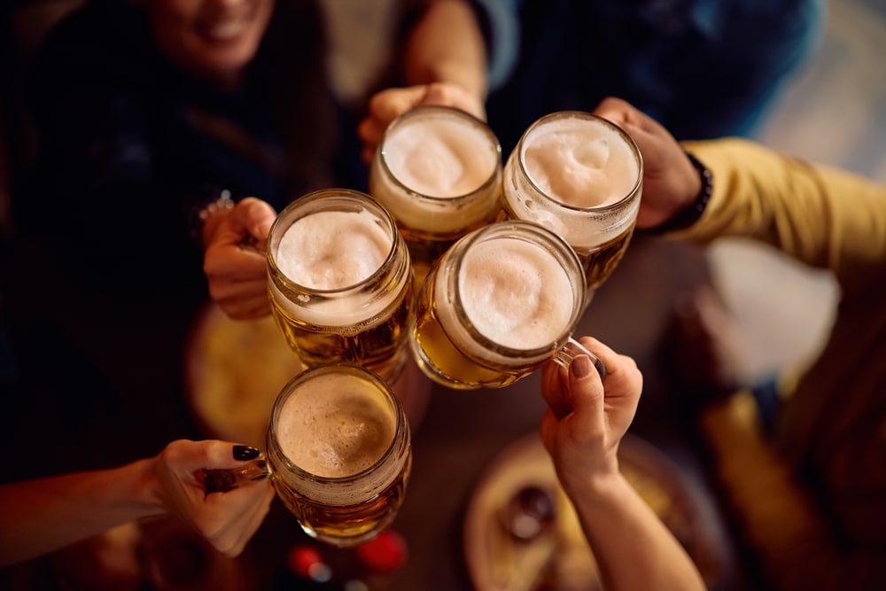 Close up of people toasting with beer glasses.