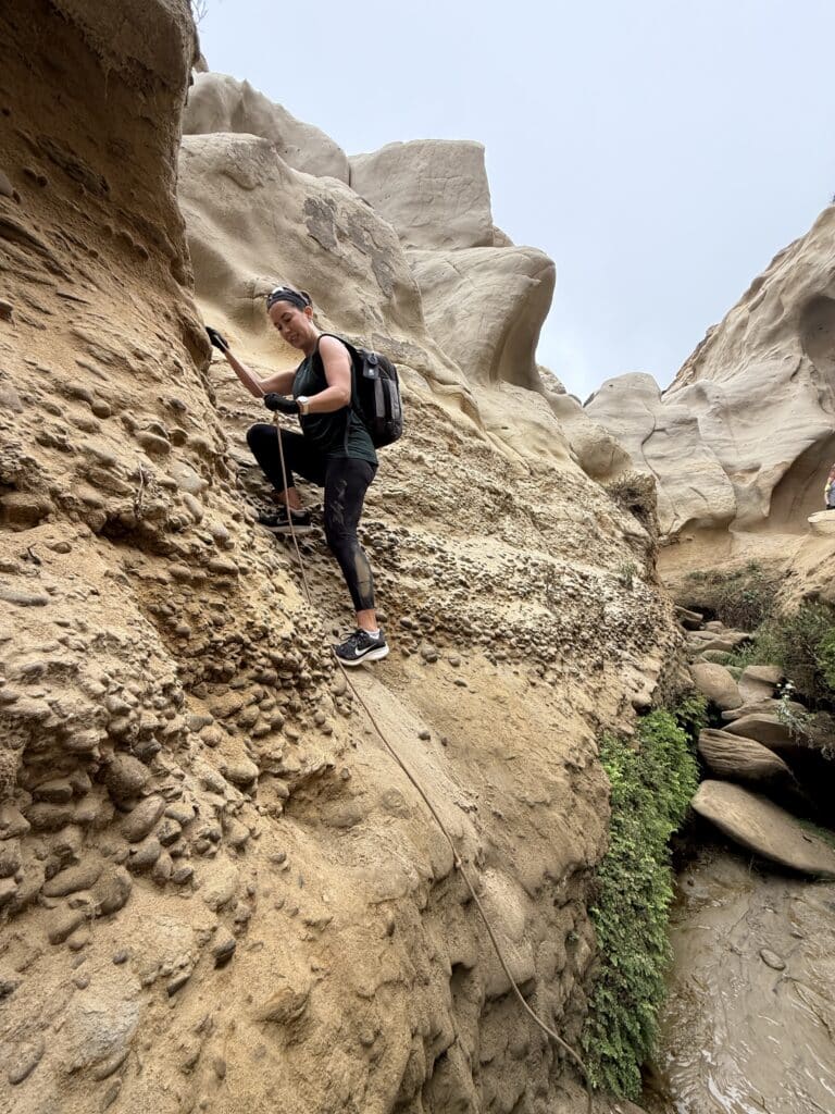 Lindsey climbing a rope on a slot canyon