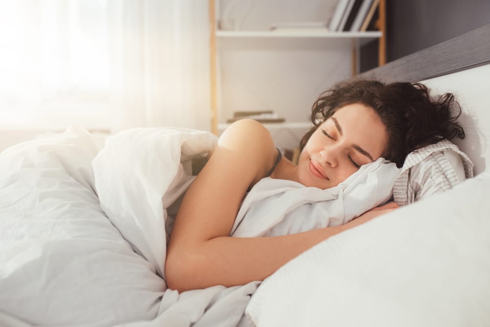 Feeling calmness. Sleepy female keeping eyes closed while dreaming about future vacation or sleeping at the bedroom. Stock photo