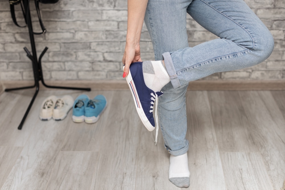 woman taking off her shoes while standing on one leg. High quality photo