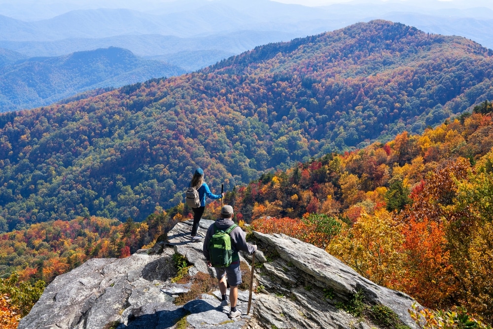 Couple hiking in the autumn mountains. Friends on top of the mountain enjoying beautiful autumn scenery. Blue Ridge Mountains, near Asheville, North Carolina, USA
